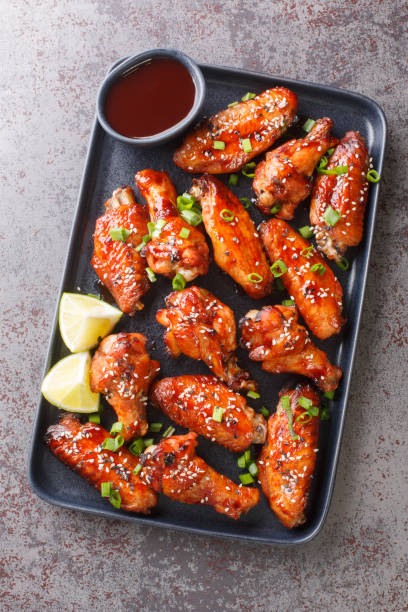Fast food fried Sticky Hoisin Wings closeup on the plate. Vertical top view Fast food fried Sticky Hoisin Wings closeup on the plate on the table. Vertical top view from above sticky sesame chicken sauces stock pictures, royalty-free photos & images