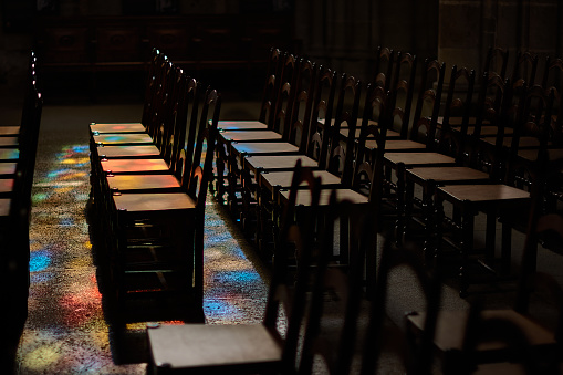 The coloured light coming through the stained glass windows of Lausanne Cathedral is reflected on their chairs. Switzerland