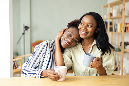 Two African American young women enjoying coffee at home together