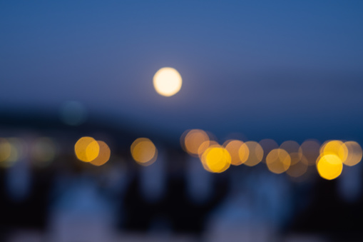Abstract horizontal photograph of city skyline with lights on and out of focus, a full moon night. Tenerife, Canary Islands, Spain.
