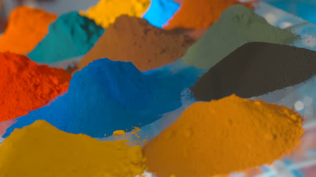 On a glass shelf, multi-colored heaps of dye in the form of a dry powder