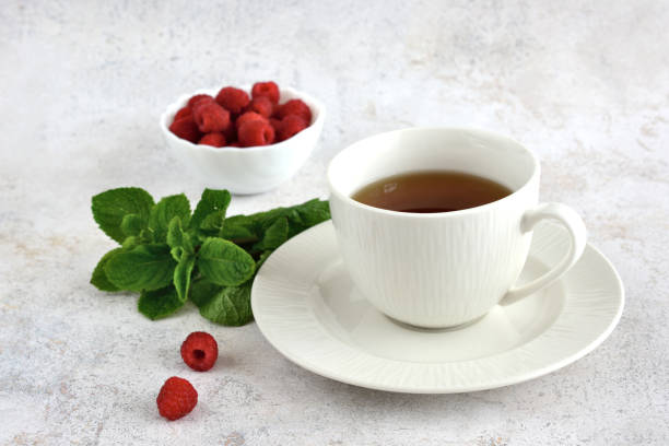 istock mint tea in white cup with saucer with mint leaf and raspberry isolated on white background 1440714162