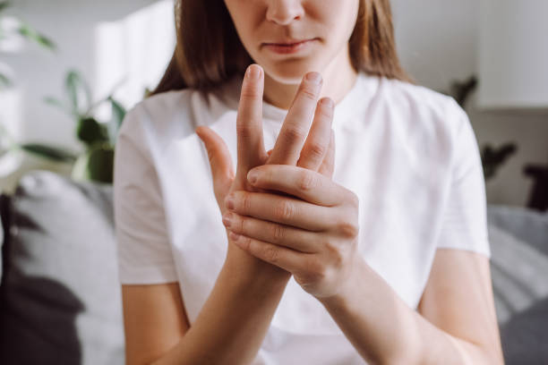 niña triste masaje de mano con dolor de muñeca, concepto de artritis reumatoide. primer plano de una mujer joven sufre de dolor adormecedor en la mano, entumecimiento de la punta del dedo, inflamación de la artritis, neuropatías periféricas - artritis fotografías e imágenes de stock