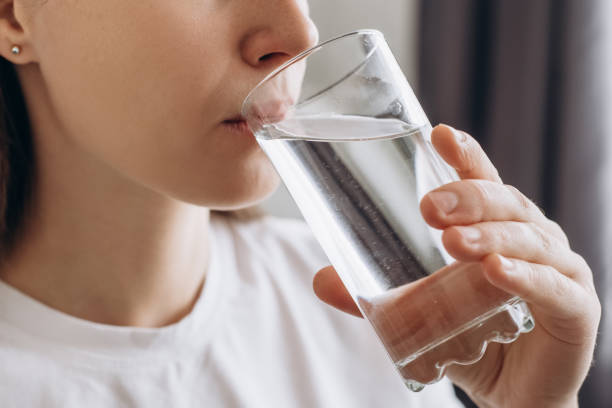 Side view close up of healthy young female drinking pure still water in morning. Caucasian lady enjoying healthy lifestyle daily habit, natural beauty, perfect skin body care aqua balance concept stock photo