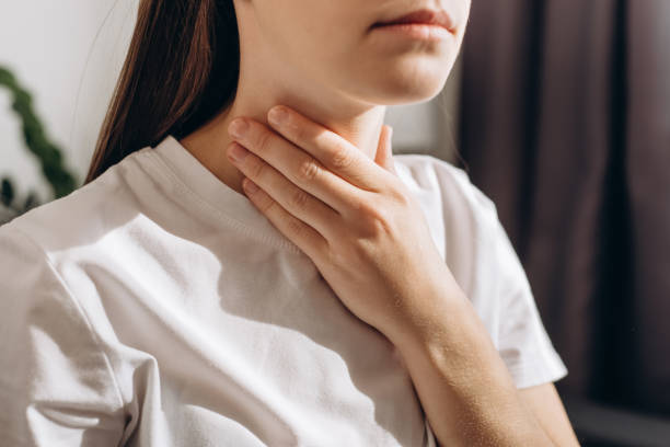 Cropped shot of female suffering from pain sitting on sofa at home. Healthcare and medical concept. Unhealthy sad young caucasian woman with sore throat inflamed tonsils from influenza symptoms Cropped shot of female suffering from pain sitting on sofa at home. Healthcare and medical concept. Unhealthy sad young caucasian woman with sore throat inflamed tonsils from influenza symptoms thyroid gland stock pictures, royalty-free photos & images