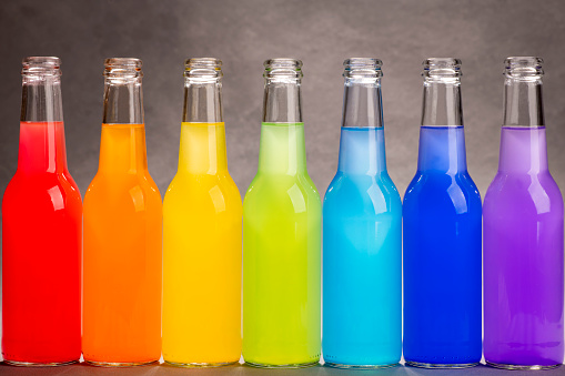Rainbow colors in bottles. Colorful rainbow background. Drinks lined up.