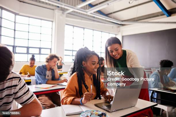 Smiling Teacher Talking With A Student Using A Laptop During A Classroom Lesson Stock Photo - Download Image Now