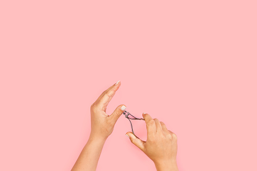 Mujer cortando su propia cutícula sobre un fondo rosa photo