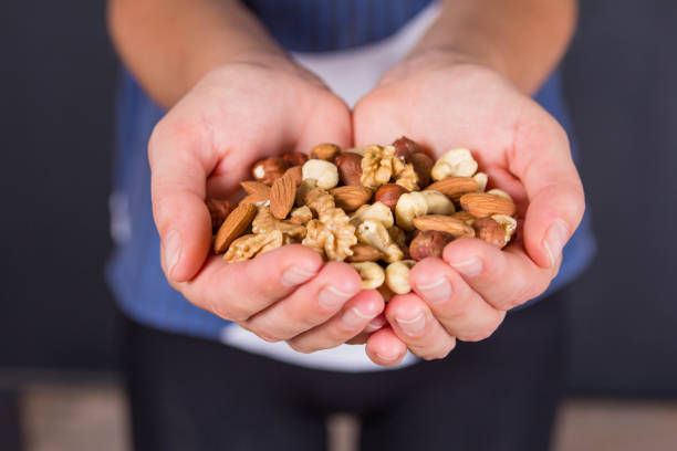 istock Women's palms filled with shelled almonds, walnuts, cashew nuts 1440720320