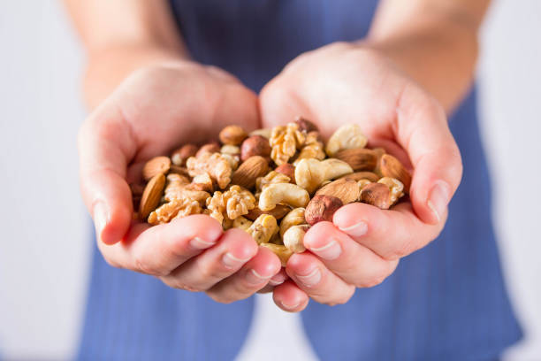 istock Women's palms filled with shelled almonds, walnuts, cashew nuts 1440720326