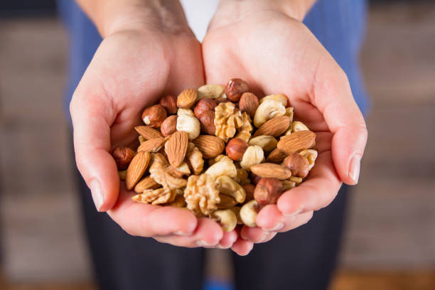 istock Women's palms filled with shelled almonds, walnuts, cashew nuts 1440720327