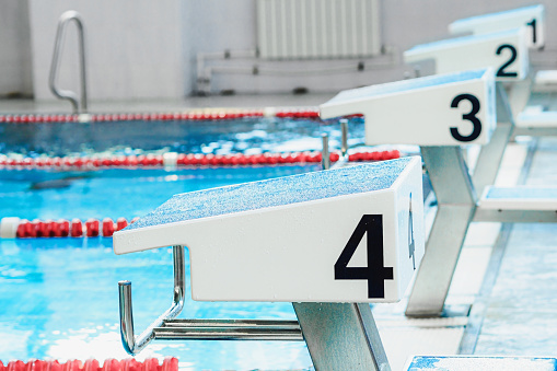 Starting table with numbers for diving in Olympic pool. Swimming pool for competitions with lane demarcation. Background..