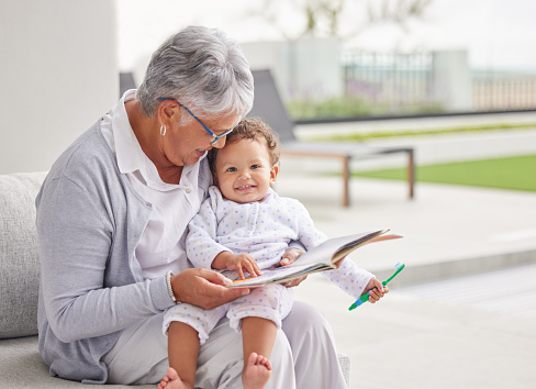 Portrait of an family, grandmother reading old book to her granddaughters, looking at book and smiling