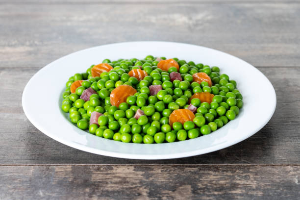 istock Green peas with serrano ham and carrot on wooden table 1440724398