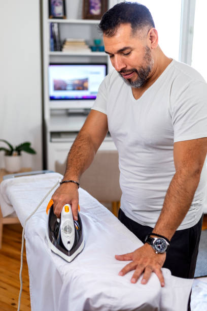 istock A  man at home ironing his button down shirt. 1440726986