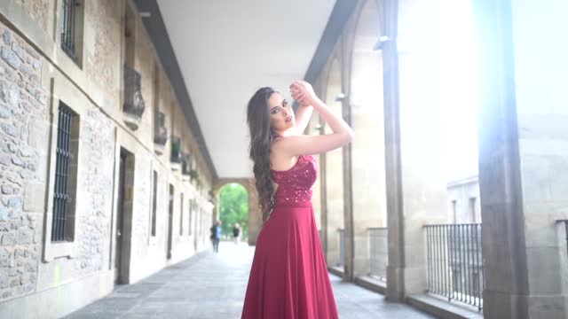 Caucasian woman in a red gala dress, model smiling walking towards the camera