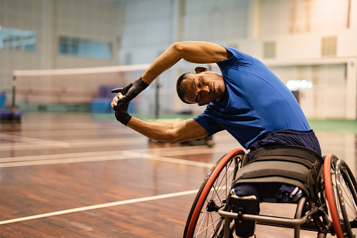 Wheelchair Asian man is doing light exercise before ready to enjoy badminton game.