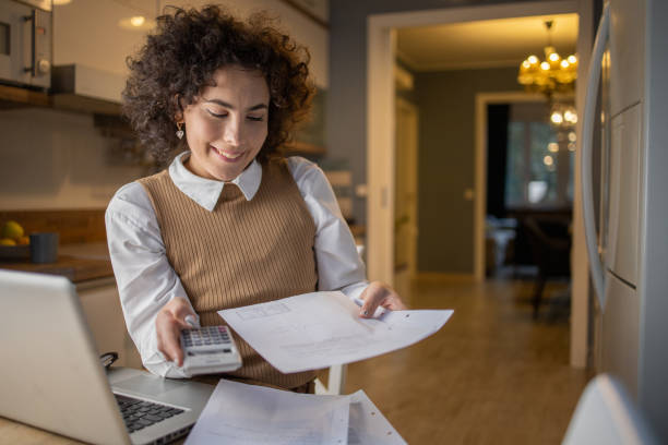 istock Young woman using a laptop and going through paperwork 1440729628