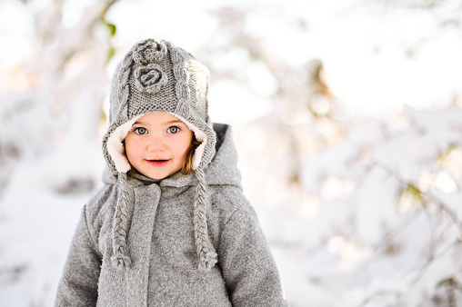 Outdoor close-up portrait of a toddler girl in a snowy nature.