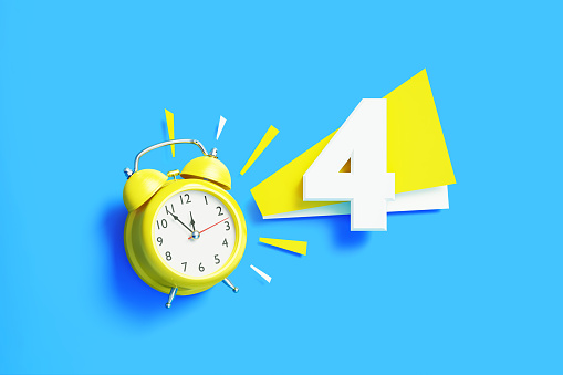 Number four sitting next to yellow alarm clock on blue background. Horizontal composition with copy space.