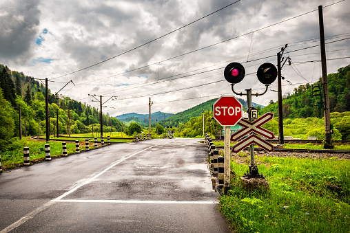 Guarded railroad crossing with open barriers, red warning light Transportation theme