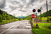 Guarded railroad crossing with open barriers, red warning light