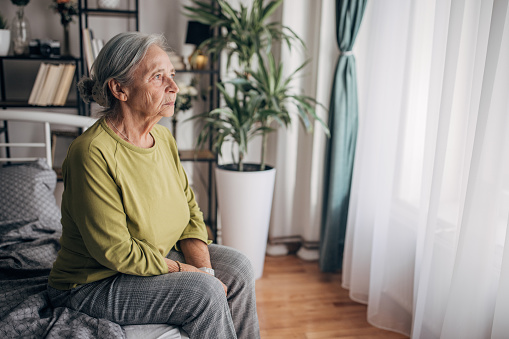 Elderly woman sitting on the bed at home