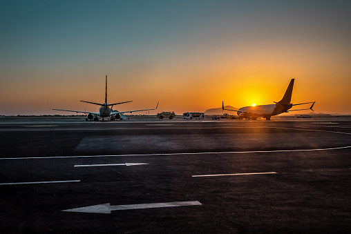 Passenger airplane on the airport runway. The plane is taking off during a colorful sunset. Transportation theme
