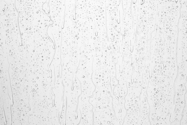 istock Drops of rain on glass against blue sky and white clouds. 1440736255