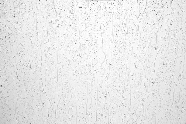 istock Drops of rain on glass against blue sky and white clouds. 1440736268