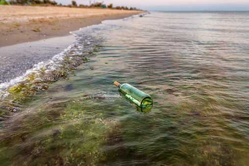 Bottle with letter in the sea water near the beach