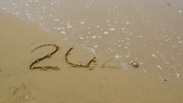 Numbers 2023 written on the sand washed away by the wave. New Year 2024 is coming. Christmas or New Year concept