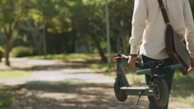 Folded electric scooter, walk in park and man on nature path for sustainable, eco friendly transportation and environmentally friendly transport. Green energy, sustainability and clean carbon travel