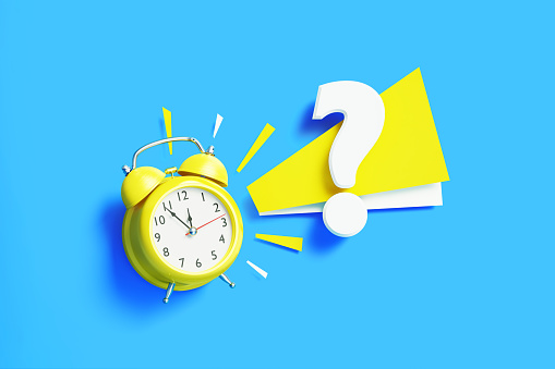 Question mark sitting next to yellow alarm clock on blue background. Horizontal composition with copy space.