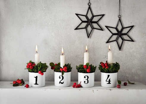4. Advent. Christmas decorations with white advent candles in four emaile pots with numbers. Handmade home decoration. Selective focus. Copy space.