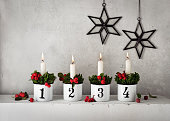4. Advent. Christmas decorations with white advent candles in four emaile pots with numbers.