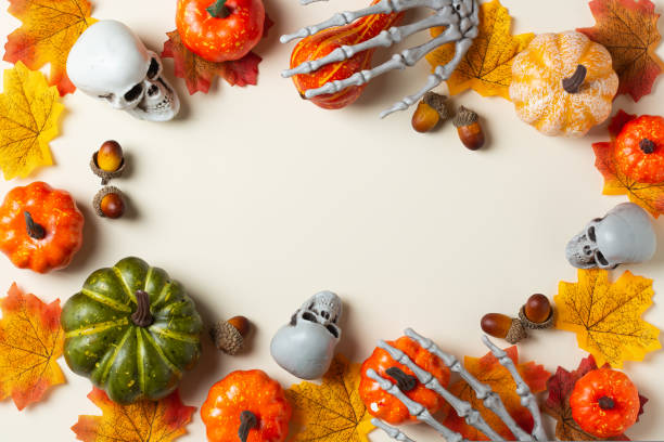istock Halloween greeting card with pumpkin, skulls, bony hands and leaves 1440740529
