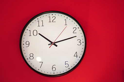 White clock wall on red wall with copy space for text,