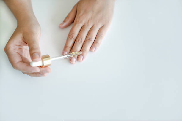 Nail and hand skin care. Woman holds pipette with oil to apply to her nails for treatment and strengthening of nails. Hands close-up, copy space Nail and hand skin care. Woman holds pipette with oil to apply to her nails for treatment and strengthening of nails. Hands close-up, no face, copy space cuticle photos stock pictures, royalty-free photos & images