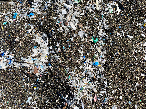 Micro plastics mixed in the sand of the beach. Microplastics on a beach.microplastics, washed up on dark lava sand