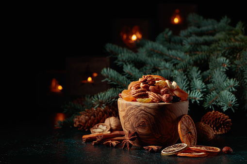 Dried fruits and assorted nuts. Christmas still-life with spruce branches and burning candles. Copy space.