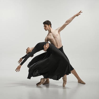 Young man and woman, ballet dancers performing on stage isolated over grey studio background. Lightness and freedom. Concept of classical dance aesthetics, choreography, art, beauty. Copy space for ad