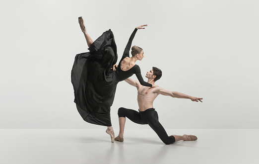 Young man and woman, ballet dancers performing isolated over grey studio background. Noble, pride dance. Concept of classical dance aesthetics, choreography, art, beauty. Copy space for ad