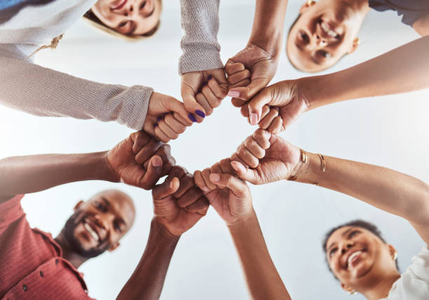 istock Teamwork, unity and hands or fist for support, trust and community below blue sky. Diversity group men and women friends standing together for teamwork, collaboration and help during team building 1440750458