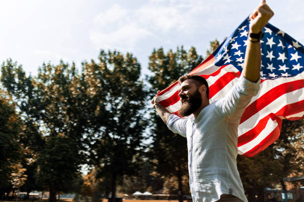istock Handsome young man waving an American flag in park 1440752409