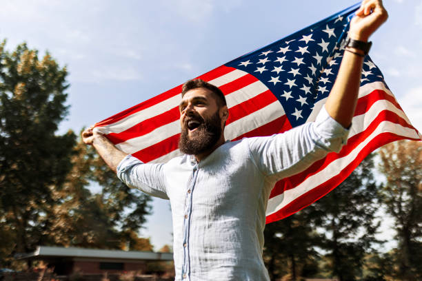 istock Handsome bearded young man waving an American flag 1440752472
