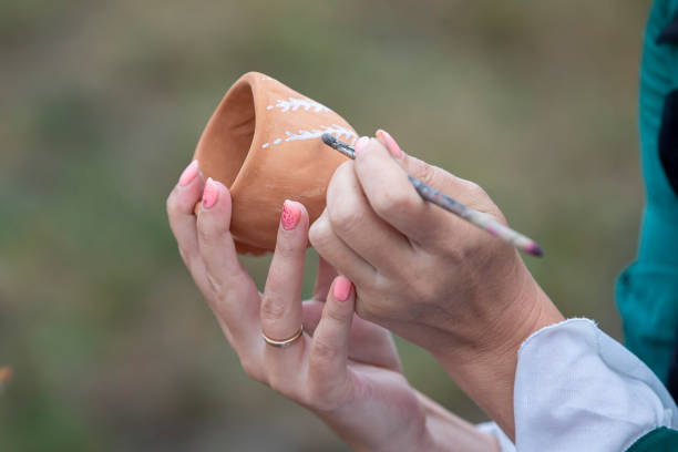 istock Paint with a brush on a clay bowl. Handicraft and tableware making. 1440752512