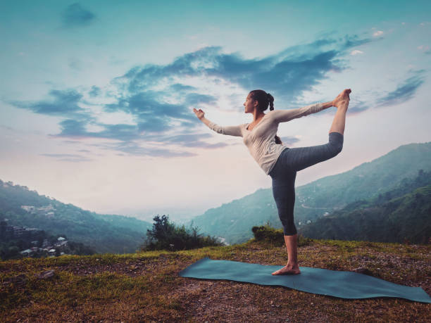 日没時に屋外でヨガアサナナカラジャサナをやっている女性 - shiva posture ストックフォトと画像