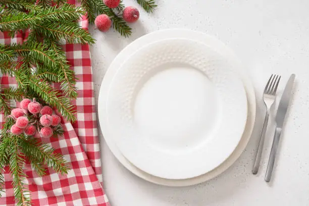 Christmas table setting with red decorative berries on white background. View from above. Copy space. Xmas dinner. Template for festive menu.