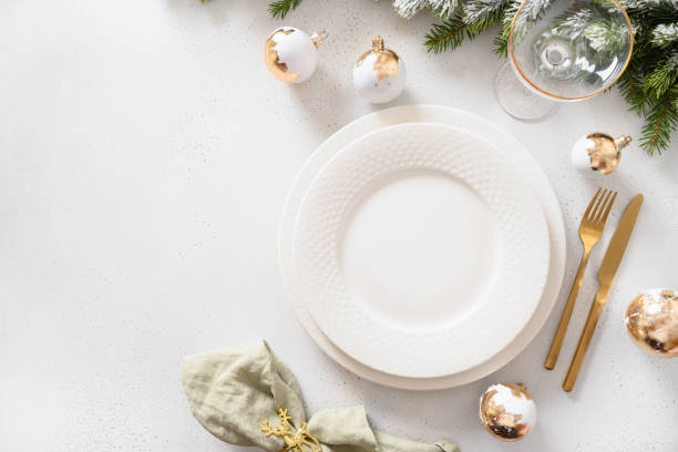 istock Beautiful Christmas festive table setting with white plate, golden balls on white. 1440753353